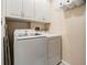 Functional laundry room with white washer and dryer, and overhead cabinets for storage at 308 Los Prados Dr # 308, Safety Harbor, FL 34695