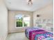 Cozy bedroom featuring a colorful patterned bed, shelving, and natural light from an arched window at 31031 Whitlock Dr, Wesley Chapel, FL 33543