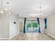 Sunlit living room featuring stylish lighting fixtures, sleek floors, and sliding glass doors to a balcony at 31031 Whitlock Dr, Wesley Chapel, FL 33543