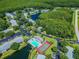 An aerial view showcases a community with lakes, a pool, and tennis courts surrounded by lush greenery at 3161 Lake Pine S Way # F1, Tarpon Springs, FL 34688