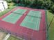 Aerial view of two fenced, modern green and red tennis courts for community recreation at 3161 Lake Pine S Way # F1, Tarpon Springs, FL 34688