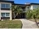 Condo building featuring lush landscaping with stone accents, palm trees and a walkway leading to the entrance at 4715 Jasper Dr # 208, New Port Richey, FL 34652