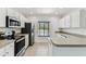 Well-lit kitchen with stainless steel appliances, white cabinetry, and tile flooring at 4927 Elizabeth Anne Cir, Tampa, FL 33616