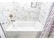 Bathroom tub featuring elegant marble-style tiling and modern gold fixtures at 4965 Puritan Cir # 401, Tampa, FL 33617