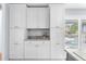 Kitchen wet bar area with white cabinets and stone countertops with a view to the exterior at 6029 Bayway Ct, New Port Richey, FL 34652