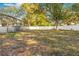 A grassy backyard with a white fence and a pool enclosure in the distance at 7948 Floral Dr, Weeki Wachee, FL 34607