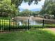 A tranquil pond, surrounded by a black fence, reflecting the lush landscape within the community at 8137 Cottonwood Ct, Seminole, FL 33776