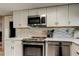 Well-equipped kitchen showcasing stainless steel appliances, stylish white cabinets, stone countertops, and a mosaic backsplash at 8417 Moulton Dr, Port Richey, FL 34668