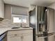 The kitchen features a stainless steel refrigerator, a modern faucet, and white cabinetry beneath a bright window at 8417 Moulton Dr, Port Richey, FL 34668