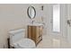 Bathroom featuring a floating wood vanity, white toilet, and urinal, enhanced by neutral-toned tile at 1201 Bay Dr, Belleair Beach, FL 33786