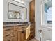 Bathroom featuring wood cabinets and drawers, granite countertop, a large rectangular mirror, and a toilet at 1201 Bay Dr, Belleair Beach, FL 33786