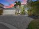 Beautiful home with a paver driveway, two-car garage, double door entry, and mature tropical landscaping at 1201 Bay Dr, Belleair Beach, FL 33786