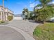 Home featuring a brick driveway, two-car garage, tropical landscaping, and serene curb appeal at 1201 Bay Dr, Belleair Beach, FL 33786