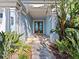 Charming front entrance with a stone pathway, tropical plants, and custom double doors at 1201 Bay Dr, Belleair Beach, FL 33786