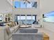 Inviting living room features comfortable seating, a large TV, and stunning water views from expansive windows at 1201 Bay Dr, Belleair Beach, FL 33786