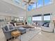 Bright, modern living room with a large sectional, waterfront views, and floor-to-ceiling windows at 1201 Bay Dr, Belleair Beach, FL 33786