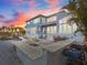 An evening view of the home showcasing a stone patio with outdoor kitchen, dining area, water feature and waterfront views at 1201 Bay Dr, Belleair Beach, FL 33786