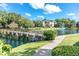 View of bridge crossing the pond to the community featuring lush grass, trees, and fountain at 14130 Rosemary Ln # 3203, Largo, FL 33774