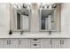 Bathroom featuring double sinks, framed mirrors, and white cabinets at 14820 Rue De Bayonne # 205, Clearwater, FL 33762