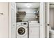Laundry closet with a stacked washer and dryer, shelving, and a toilet at 14820 Rue De Bayonne # 205, Clearwater, FL 33762