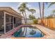 A brick pool deck surrounds a sparkling pool, screened-in porch and lush palm trees at 2031 Tanglewood Ne Way, St Petersburg, FL 33702