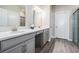 Bright bathroom featuring double sinks, white countertop, gray cabinets, and a large mirror at 31837 Cannon Rush Dr, San Antonio, FL 33576