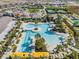 Aerial shot of the community pool with ample seating, palm trees, and clubhouse with tennis courts at 31837 Cannon Rush Dr, San Antonio, FL 33576