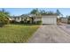 Charming single-story home featuring a lush green lawn, palm trees, and a convenient attached garage at 3218 Fauna St, Sarasota, FL 34235