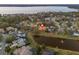Aerial view of a home with a screened-in pool, pond view, and well-maintained landscaping at 3830 Moreno Dr, Palm Harbor, FL 34685