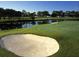 Scenic golf course view with lush green grass, a water hazard, and a sand bunker at 3830 Moreno Dr, Palm Harbor, FL 34685