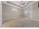 A large, well-lit carpeted main bedroom with a ceiling fan and sliding glass doors to the pool area at 3830 Moreno Dr, Palm Harbor, FL 34685