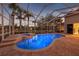 Screened in ground pool at dusk with brick patio and scenic views at 3830 Moreno Dr, Palm Harbor, FL 34685