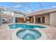 Screened-in pool with a hot tub, brick patio, and access to an outdoor living area at 3830 Moreno Dr, Palm Harbor, FL 34685