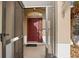 View through the screened front door toward the solid red door with sidelights, decorative transom, and 