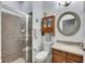 Well-lit bathroom with a tiled shower, a cabinet, modern fixtures, and an oval framed mirror at 5326 Loon Nest Ct, Apollo Beach, FL 33572