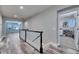 Hallway leading to a living room and bedroom featuring hardwood floors, a dark railing and neutral walls at 5326 Loon Nest Ct, Apollo Beach, FL 33572