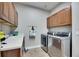 Well-equipped laundry room featuring stainless steel washer and dryer, sink, and ample storage cabinets at 5326 Loon Nest Ct, Apollo Beach, FL 33572