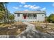 Charming single-story home with a metal roof, inviting front porch, and vibrant red front door at 6131 Central Ave, New Port Richey, FL 34653