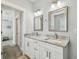 Bathroom with a double vanity featuring granite counters and framed mirrors, with a view to other rooms in the house at 7403 S Obrien St, Tampa, FL 33616