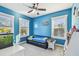 Vibrant blue bedroom featuring large windows, a modern ceiling fan, and a playful fish tank at 7403 S Obrien St, Tampa, FL 33616