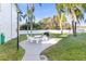 Spacious backyard with a patio set, grill, palm trees, and white privacy fence at 952 Virginia St # 108, Dunedin, FL 34698