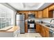 Bright kitchen featuring wood cabinetry, stainless steel appliances, and granite countertops at 952 Virginia St # 108, Dunedin, FL 34698