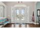 Inviting foyer showcasing hardwood floors, glass-paneled double doors, and tasteful decor with an American flag at 9606 Braden Run, Bradenton, FL 34202