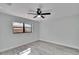 Bedroom with wood-look floors, ceiling fan, and large window providing natural light at 11283 Portsmouth St, Spring Hill, FL 34609