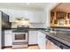 Compact kitchen featuring white cabinets, speckled countertops, stainless steel appliances, and tile flooring at 11743 Rolling Pine Ln, Port Richey, FL 34668