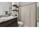 Bathroom features a dark vanity with granite countertop, a shower with curtain, and open wood shelves at 11912 Richmond Trl, Parrish, FL 34219