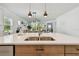 Up close view of kitchen island with double sink, stainless steel dishwasher, and view to dining area at 11912 Richmond Trl, Parrish, FL 34219