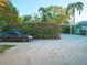 Paved driveway leads to a carport and backyard, framed by lush tropical landscaping and a parked car at 148 93Rd Ave, Treasure Island, FL 33706