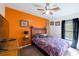 Bright bedroom with an orange accent wall, wooden furniture, and a large comfortable bed at 15429 Green Jay Rd, Weeki Wachee, FL 34614