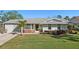 Charming single-story home features a well-manicured lawn, palm trees, and decorative flowerbeds at 18350 Burkholder Cir, Port Charlotte, FL 33948